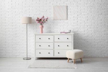 Modern oturma odasındaki çekmecelerin üzerinde güzel manolya çiçekleri olan vazo.