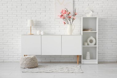 Modern oturma odasındaki çekmecelerin üzerinde güzel manolya çiçekleri olan vazo.