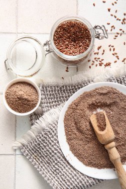 Beyaz fayans zemininde tohumlu keten unu ve kavanoz.