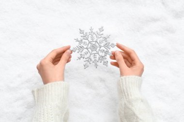 Karda süslü kar taneleri olan kadın elleri.