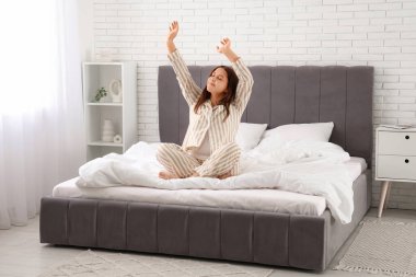 Güzel genç bir kadın sabahları yatakta geriniyor.