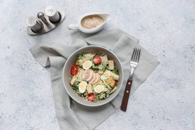 Lezzetli tavuklu Sezar salatası ve beyaz arka planda sos teknesi.