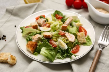 Lezzetli tavuklu Sezar salatası ve gri arka planda sos teknesi, yakın plan.