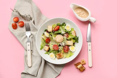 Lezzetli Sezar salatası ve pembe arka planda sos kabı.