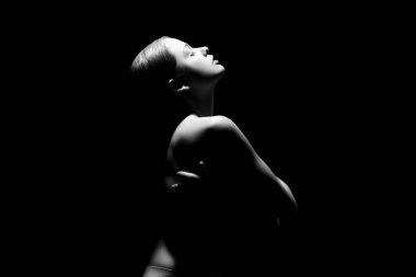 Karanlık arka planda çekici genç bir kadının silueti.