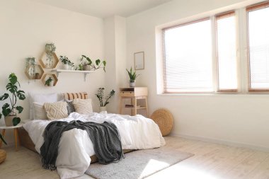 Yeşil bitkilerle, raflarla ve masalarla aydınlık yatak odasının içi