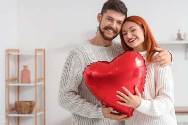 Evde kalp şeklinde balonları olan genç ve güzel bir çift. Sevgililer Günü kutlaması