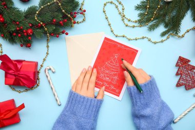 Güzel tebrik kartı, kalem, Noel hediyeleri ve renk arkaplanı süslemeleri olan kadın elleri.