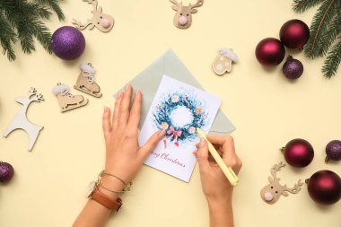 Renkli arka planda güzel tebrik kartı, kalem ve Noel süslemeleri olan kadın elleri, yakın plan