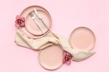 Pembe arka planda güzel orkide çiçekleri olan şık masa ayarları