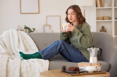 Güzel, genç, mutlu bir kadın. Bir fincan kahve ve kitaplarla evde oturuyor.