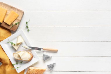 Lezzetli peynirli kompozisyon, taze ekmek ve hafif ahşap arka planda mikro yeşil