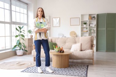 Evde elinde KETO diyeti ve mezura ile terazi tutan genç bir kadın