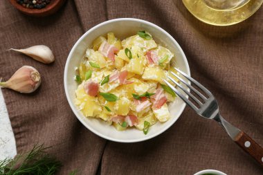 Bir kase lezzetli patates salatası, yeşil, pastırma ve peçeteli sarımsak.