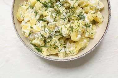 Beyaz arka planda dereotlu patates salatası.