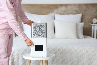 Yatak odasında hava nemlendirici kullanan bir kadın.