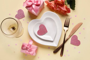 Hediye kutuları ve sarı arka planda güzel güller olan şık bir masa. Sevgililer Günü kutlaması