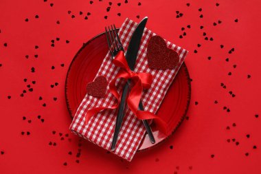 Kalpler ve kırmızı arka planda konfeti olan güzel bir masa. Sevgililer Günü kutlaması