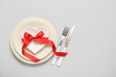 Kalp şeklinde tabağı ve gri arka planda kurdelesi olan güzel bir masa. Sevgililer Günü kutlaması