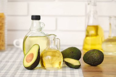 Beyaz tuğla duvarın yanındaki ahşap masada bir şişe taze avokado yağı.