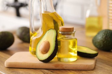 Bir şişe taze yağ ve ahşap masa üzerinde avokado.