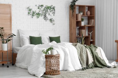 Yatak odasının içinde raf ünitesi ve yeşil bitkiler var.