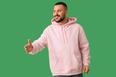 Genç adam yeşil arka planda el sıkışmaya uzanıyor. Kural kavramı