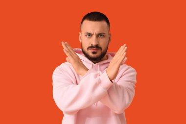 Genç adam turuncu arka planda DUR hareketi gösteriyor. Kural kavramı