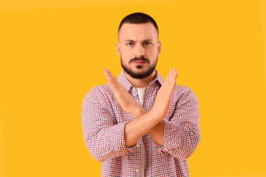 Genç adam sarı arka planda DUR hareketi gösteriyor. Kural kavramı