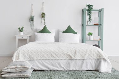 Yatak odasının içinde raf ünitesi, masa ve yeşil bitkiler var.