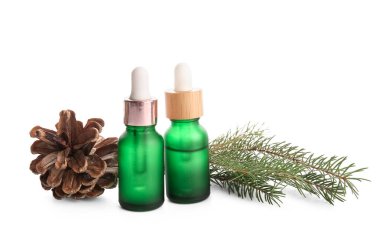 Beyaz zemin üzerinde çam kozalağı ve köknar dalı olan gerekli yağ şişeleri