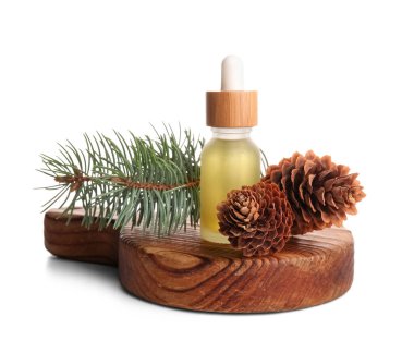 Çam kozalaklı bir şişe yağ ve beyaz arka planda köknar dalı.