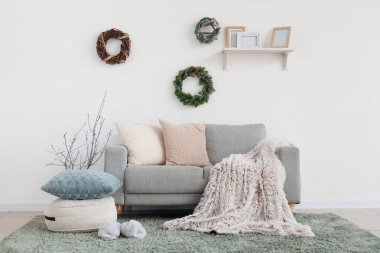 Oturma odasının içinde kanepe ve Noel çelenkleri var.