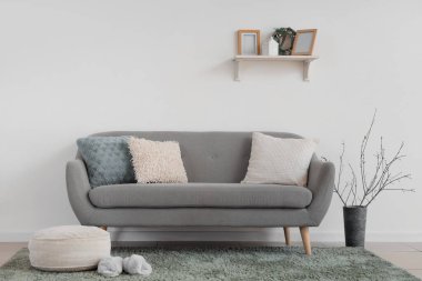 İçinde kanepe, puf ve ağaç dalları olan bir vazo.