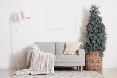 Oturma odasının içinde kanepe, lamba ve Noel ağacı var.