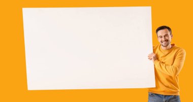 Sarı arka planda boş posteri olan adam.