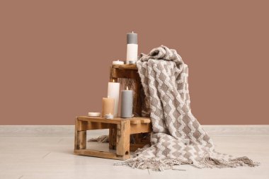 Odanın yanındaki kahverengi duvarda yanan mumlar ve ekoseli tahta kutular.