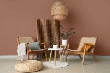 Modern odanın içinde rahat koltuklar, sedirler ve kahverengi duvarın yanındaki ev bitkileri.