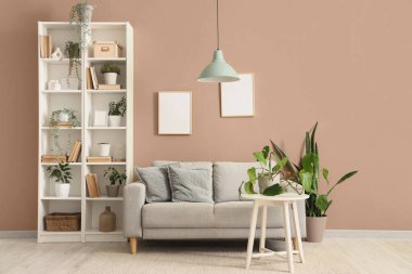 Gri kanepesi, raf ünitesi ve yeşil bitkileri olan oturma odasının içinde.