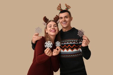 Geyik boynuzlu, bej arka planda dekoratif kar taneleri olan güzel bir çift.