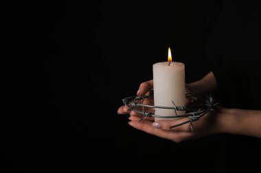 Karanlık arka planda yanan mum ve dikenli telleri olan Yahudi kadın, yakın plan. Uluslararası Soykırım Anma Günü