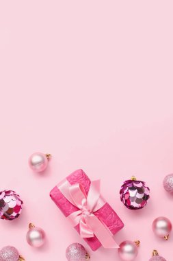 Pembe arka planda hediyeli Noel ağacı topları