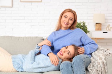 Mutlu genç kadın ve annesi evdeki kanepede. Uluslararası Sarılma Günü