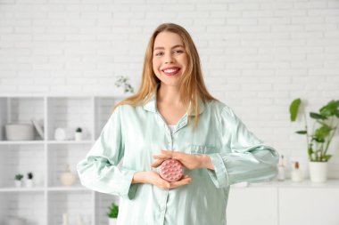 Evde pijamalı, saç derisi masaj aleti olan genç bir kadın var.