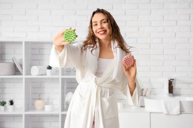 Banyoda saç derisi masajcısı olan genç bir kadın.