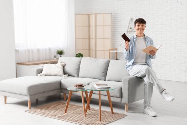 Çikolatalı ve kitaplı yakışıklı genç adam oturma odasında.