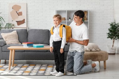 Baba, küçük oğlunun sırt çantasını evde ayarlıyor.