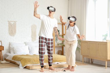 Yatak odasında VR gözlüğü kullanan genç bir çift.