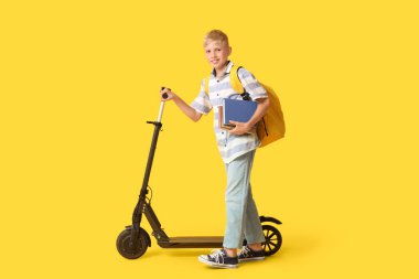 Modern elektrikli scooter, kitaplar ve sarı arka planda sırt çantası olan sevimli bir okul çocuğu.