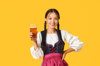 Sarı arka planda bir bardak birayla genç bir Ekim Festivali garsonu.